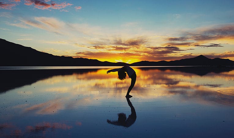 Adolescente en pose de yoga al atardecer en Salar en Bolivia